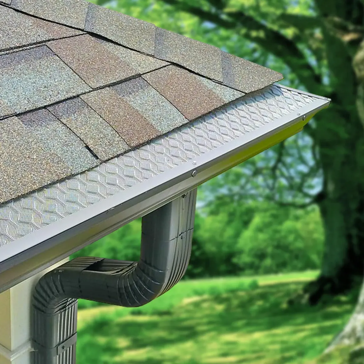 Perforated gutter guard seated over a seamless gutter run at the roof edge